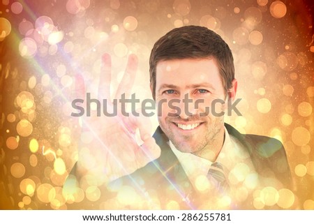 Businessman smiling and making ok sign against yellow abstract light spot design