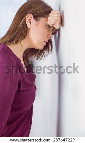 Depressed woman leaning her head against a wall on white background