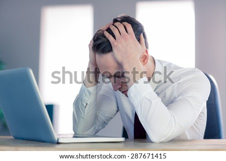 Worried businessman with head in hands in the office