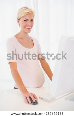 Portrait of a blonde pregnant using computer in the office