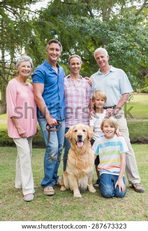 Happy family smiling at the camera with their dog on a sunny day