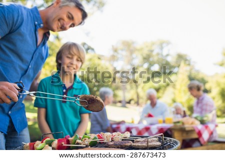 Happy father doing barbecue with his son on a sunny day