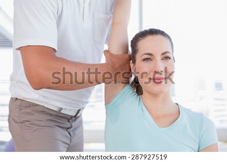 Woman stretching her arm with trainer in fitness studio