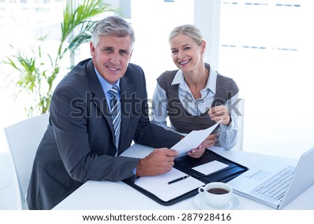 Smiling businessman with secretary checking file in an office