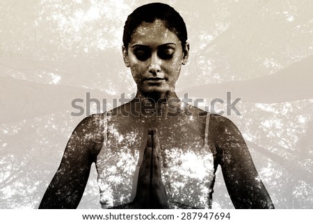 Peaceful woman in white sitting in lotus pose against low angle view of tall trees