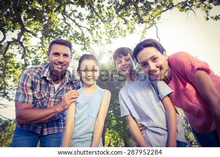 Happy family smiling at camera in the park on a sunny day