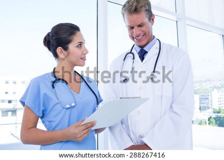 Happy doctors looking at clipboard in medical office