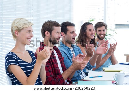 Young business people clapping hands in meeting at the office