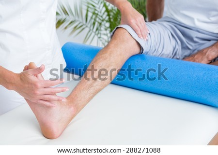 Doctor examining her patient leg in medical office