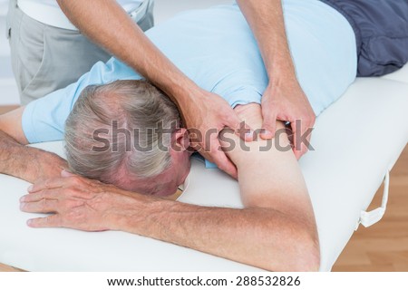 Physiotherapist doing shoulder massage to his patient in medical office