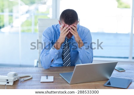 Worried businessman with head in hands in an office