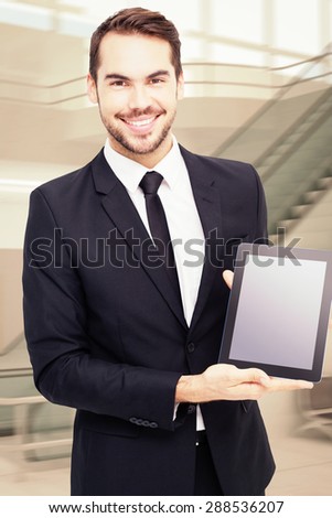 Smiling businessman showing his tablet pc against airport terminal