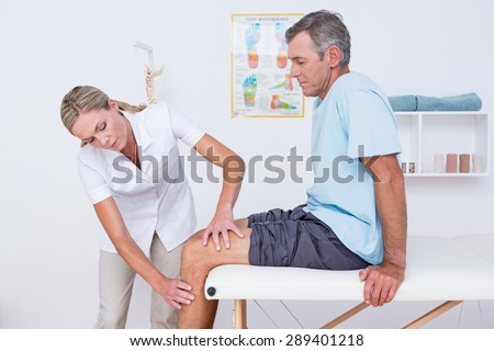 Doctor examining her patient knee in medical office