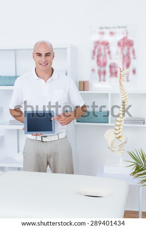 Smiling doctor showing laptop pc in medical office