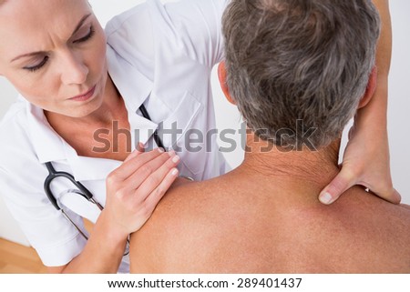 Doctor examining her patient shoulder in medical office
