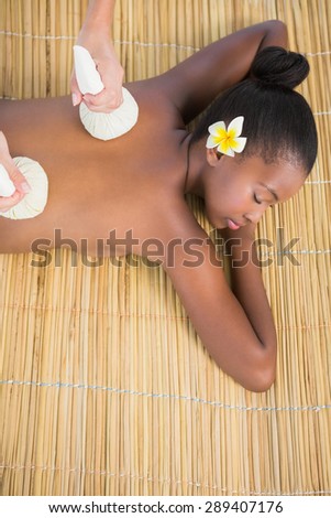 Upward view of a pretty woman enjoying a herbal compress massage at the health spa