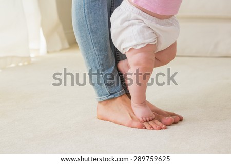 Happy mother with her baby girl learn to walk at home in the living room
