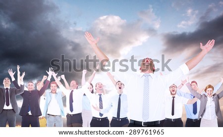 Handsome businessman cheering with arms up against blue and orange sky with clouds