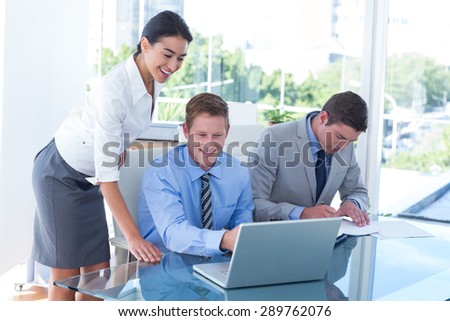 Three young business people using laptop in office
