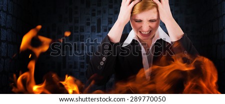 Stressed businesswoman with hands on her head against dark grey room