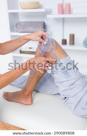 Doctor examining man leg with tool in medical office