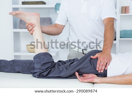 Physiotherapist doing leg massage to his patient in medical office