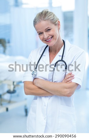 Beautiful smiling doctor standing arms crossed in hospital room