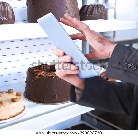 Businessman scrolling on his digital tablet against close up of desert like swiss roll and coffee cake