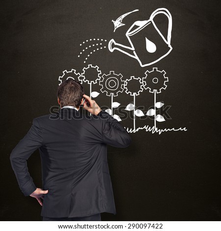 Thinking businessman scratching head against blackboard