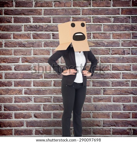 Businesswoman with box over head against red brick wall