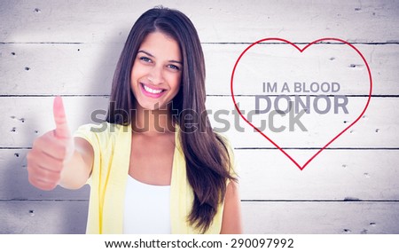 Happy casual woman showing thumbs up against white wood