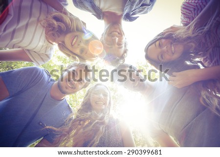 Happy friends huddling in circle in the park on a sunny day