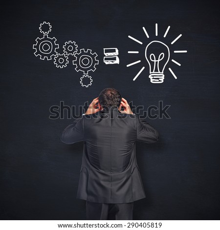 Stressed businessman with hands on head against blackboard