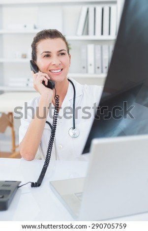 Doctor doing phone call while she using computer in medical office
