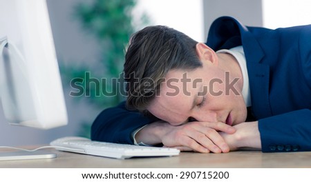 Exhausted businessman sleeping at his desk in his office
