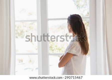 Beautiful brunette woman looking out in window at home