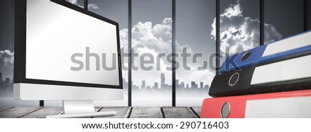 Computer screen against room with large window looking on city skyline