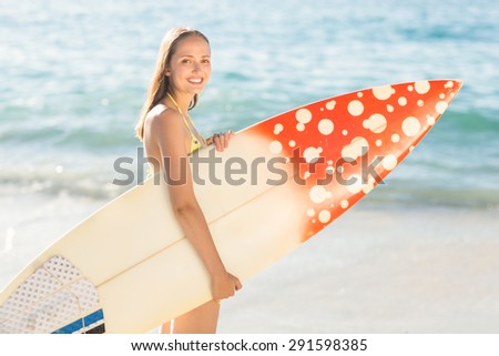 Pretty brunette holding surf board at the beach