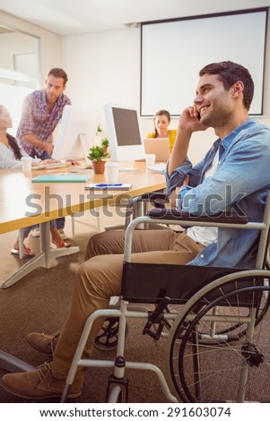 Creative businessman in wheelchair on the phone at office