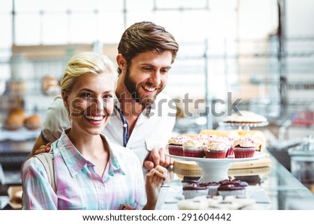 Cute couple on a date looking at cakes at the bakery