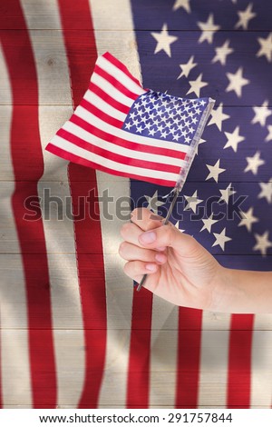 Hand waving american flag against pale grey wooden planks
