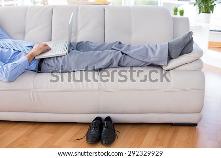 Businessman using his laptop on couch in living room