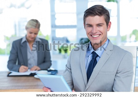 Smiling businessman looking at camera and holding a file in an office