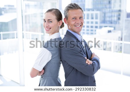 Two business colleagues standing back to back in the office
