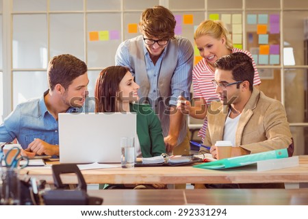 Happy creative business team using laptop in meeting at office