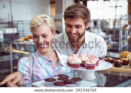 Cute couple on a date pointing chocolate cakes at the bakery