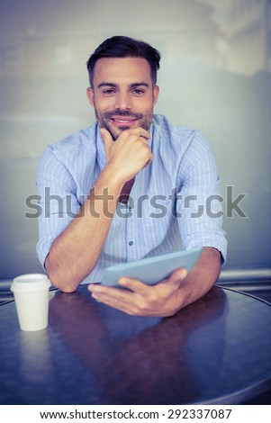 Portrait of smiling businessman using a tablet outside the cafe