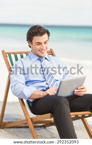 Businessman using his tablet pc at the beach