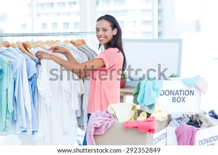 Portrait of a smiling young female volunteer separating clothes