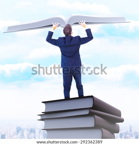 Businessman climbing on a cube with arms out against city on the horizon